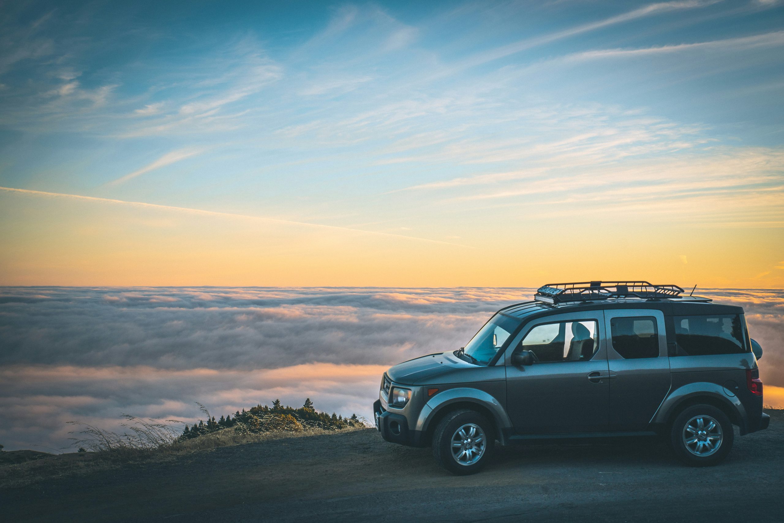 Sport Utility Vehicle overlooking a scenic vista covered in clouds on its road trip